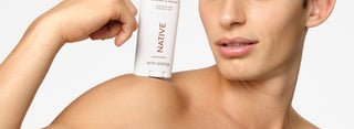 Person holding a bottle of Native skincare product on a white background